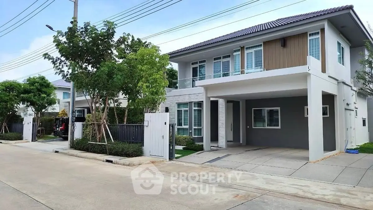 Modern two-story house with spacious driveway and lush greenery in a serene neighborhood.