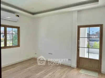 Spacious empty room with wooden flooring and large windows, perfect for customization.