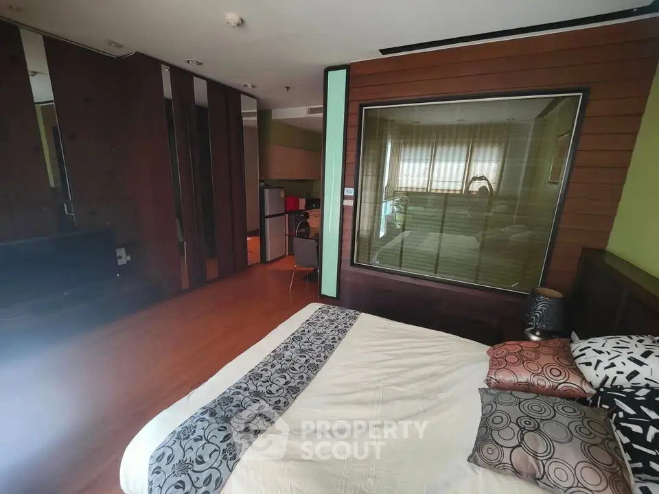 Spacious bedroom with modern decor and large window overlooking interior space.