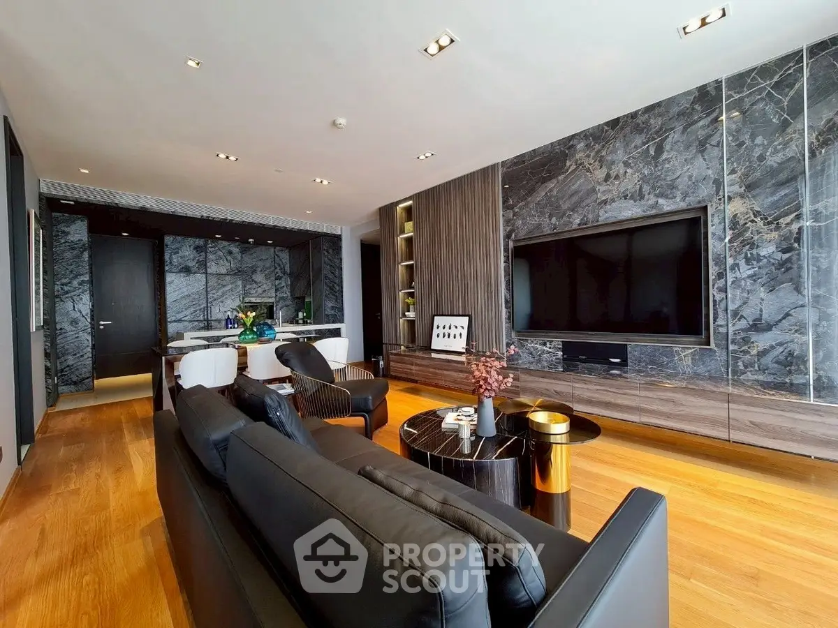 Luxurious modern living room with sleek black leather sofas, large TV, and elegant marble accents.