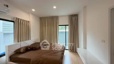 Spacious bedroom with modern decor and large windows for natural light.