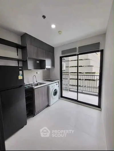 Modern kitchen with washing machine and balcony view in sleek apartment.
