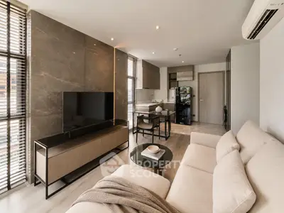 Modern living room with sleek furniture and open kitchen layout, featuring a large TV and stylish decor.