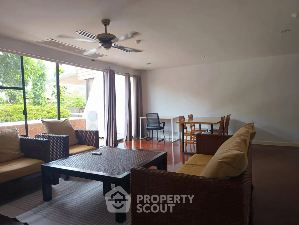Spacious living room with modern furniture and large windows overlooking greenery.
