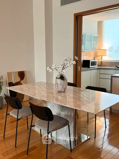 Modern dining area with marble table and open kitchen layout in stylish apartment.
