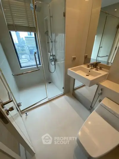 Modern bathroom with city view, featuring glass shower and sleek fixtures.