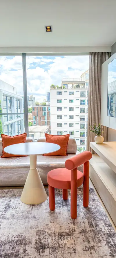 Modern living room with stylish furniture and city view, featuring large windows and contemporary decor.