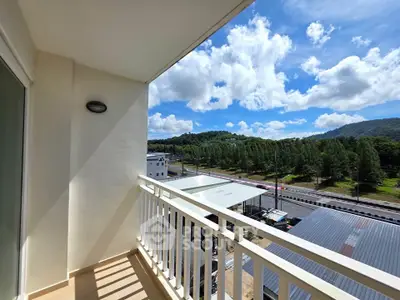 Spacious balcony with scenic view of lush greenery and blue skies, perfect for relaxation.