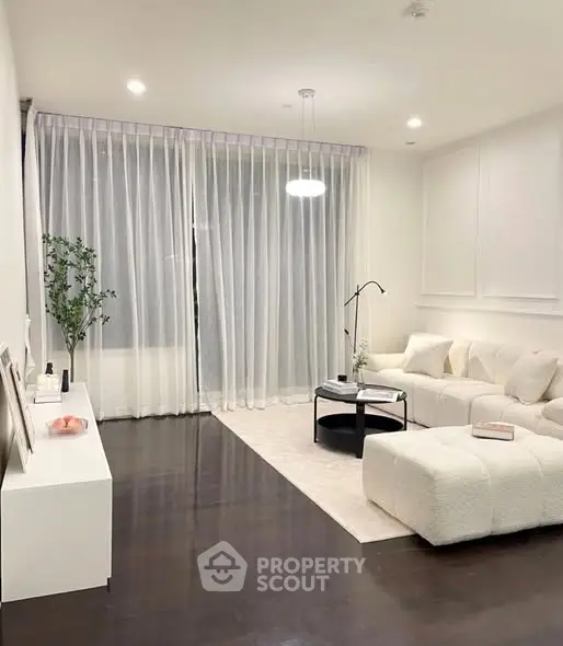 Elegant modern living room with plush white furniture and floor-to-ceiling curtains.