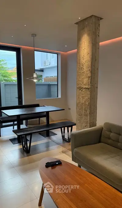 Modern living room with industrial design, featuring exposed concrete pillar and stylish furniture.