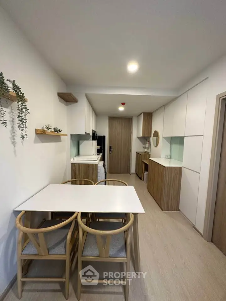Modern kitchen with sleek cabinetry and dining area, featuring a minimalist design and warm wooden accents.