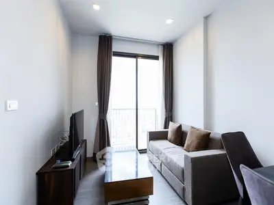 Modern living room with sleek furniture and large window offering natural light.