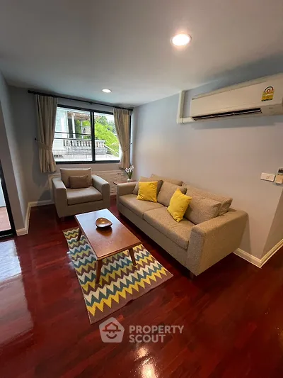 Cozy living room with modern furniture and air conditioning, featuring hardwood floors and natural light.