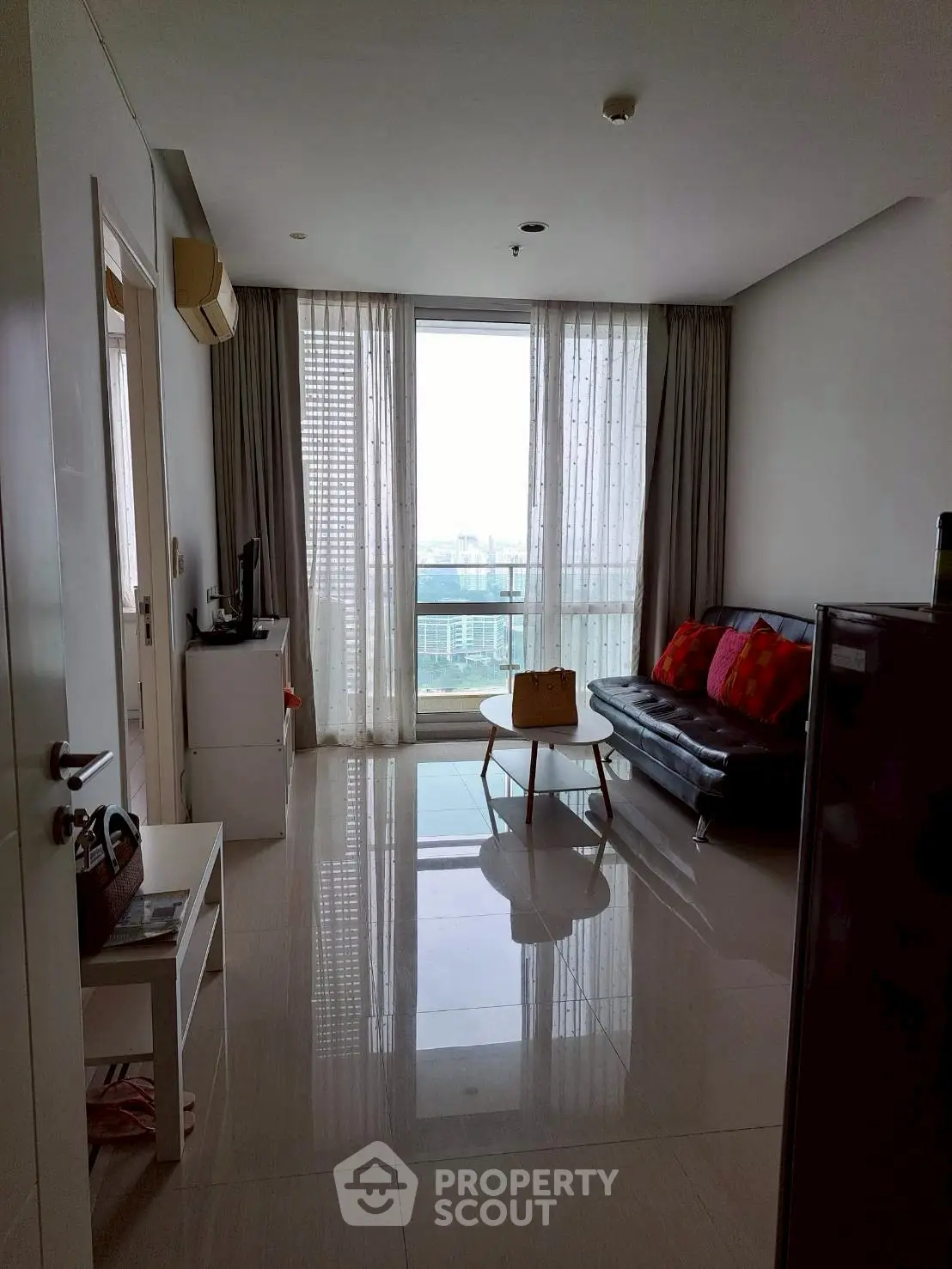 Modern living room with sleek furniture and city view through large windows, perfect for urban living.