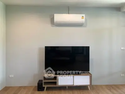 Modern living room with sleek TV setup and air conditioning, perfect for comfortable living.
