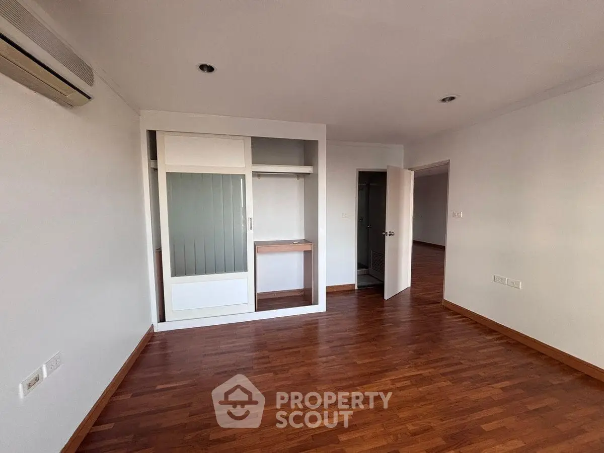 Spacious bedroom with wooden flooring and built-in wardrobe