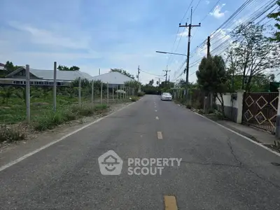 Scenic suburban road with lush greenery and residential buildings, perfect for peaceful living.
