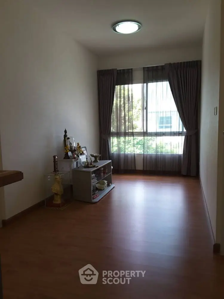 Bright room with wooden flooring and large window, perfect for a cozy setup.