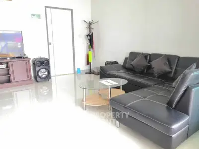 Modern living room with sleek black leather sofa and glass coffee table, perfect for relaxation and entertainment.