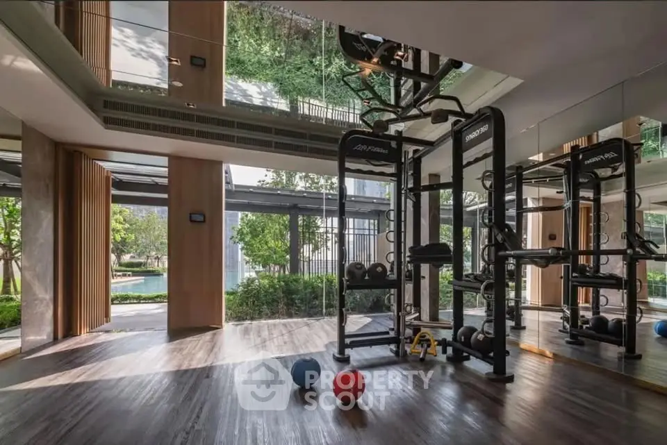 Luxurious gym with modern equipment and garden view in upscale residential complex.