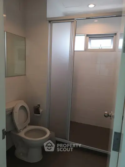 Modern bathroom with shower and toilet, featuring sleek design and natural light.