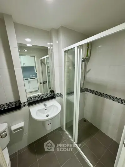 Modern bathroom with sleek shower and stylish sink in contemporary apartment.