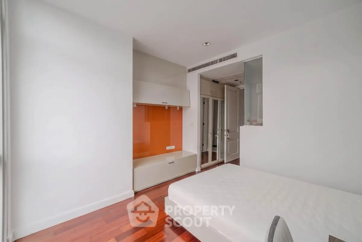 Modern bedroom with sleek design and hardwood floors in a contemporary apartment.