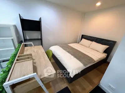 Modern bedroom with cozy bed and stylish desk, perfect for urban living.