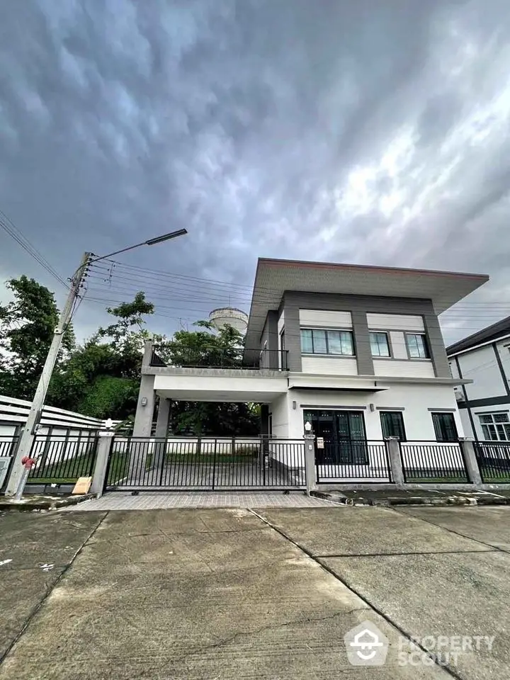 Modern two-story house with sleek design and spacious driveway under cloudy sky