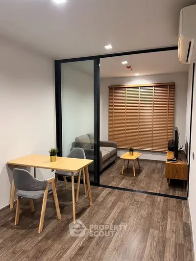 Modern living room with wooden flooring, glass partition, and stylish furniture in a cozy apartment.