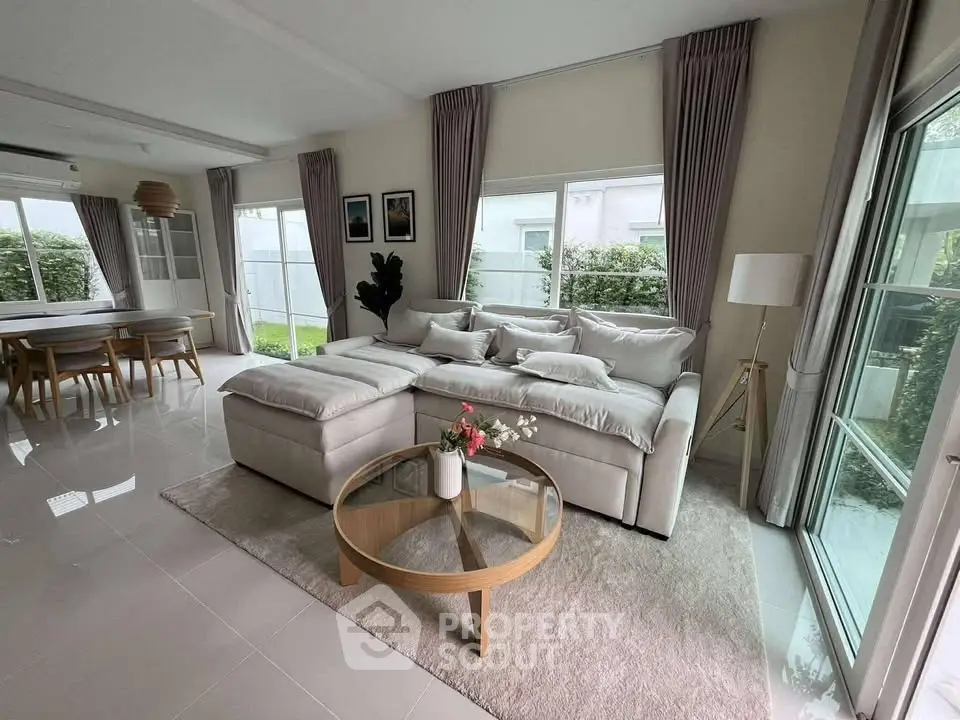 Spacious modern living room with large windows and elegant dining area, perfect for family gatherings.