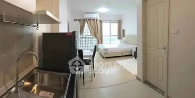 Modern studio apartment with open kitchen and cozy bedroom area, featuring large windows and natural light.