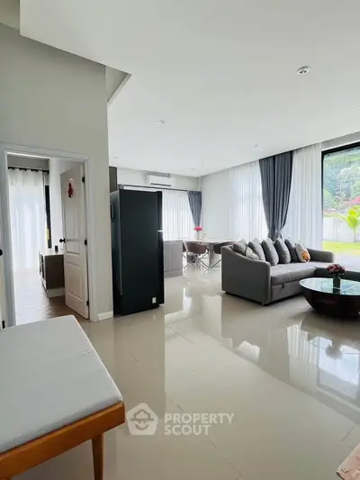 Spacious modern living room with elegant decor and large windows offering natural light.