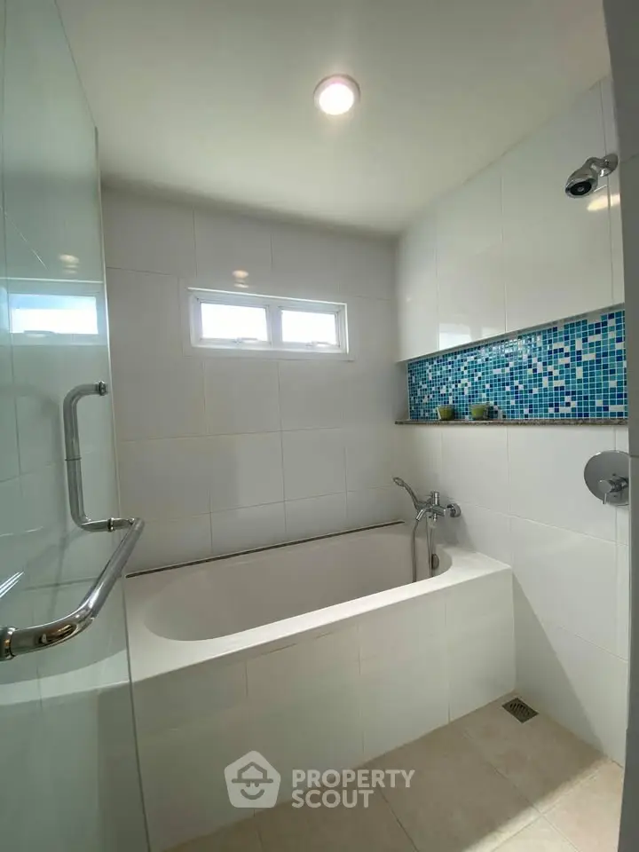 Modern bathroom with stylish bathtub and mosaic tile accent wall