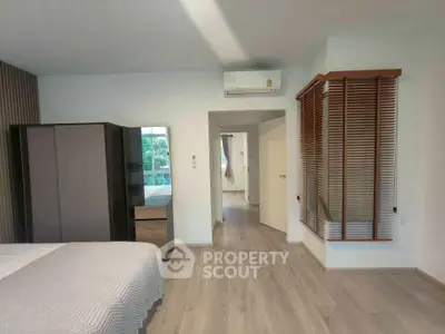 Spacious modern bedroom with wooden flooring and air conditioning