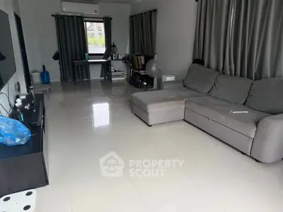 Spacious living room with modern gray sectional sofa and sleek tile flooring.