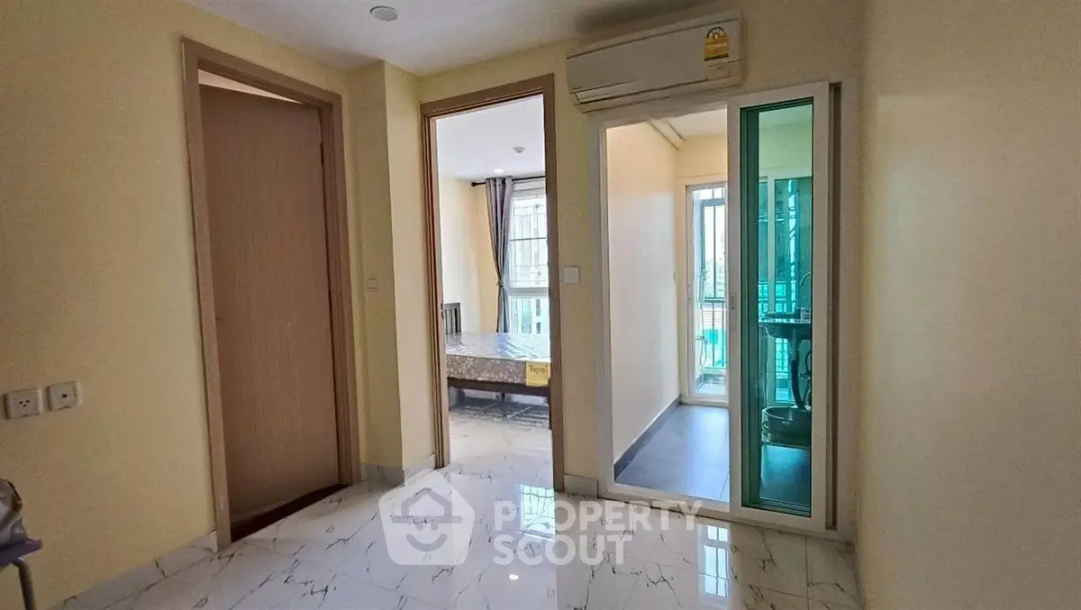 Bright apartment interior with marble flooring and air conditioning, featuring a glimpse of a balcony.