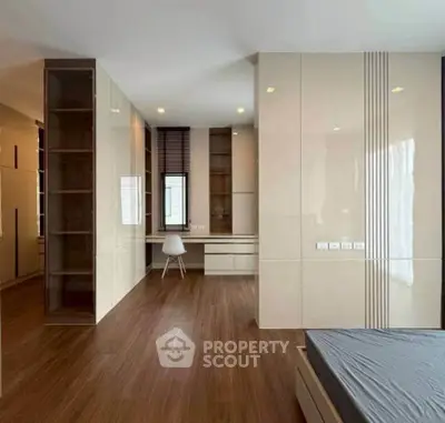 Spacious modern bedroom with sleek built-in storage and elegant wood flooring.