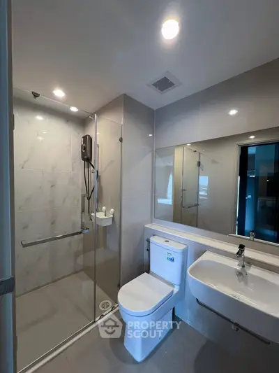 Modern bathroom with glass shower and sleek fixtures in a contemporary home.