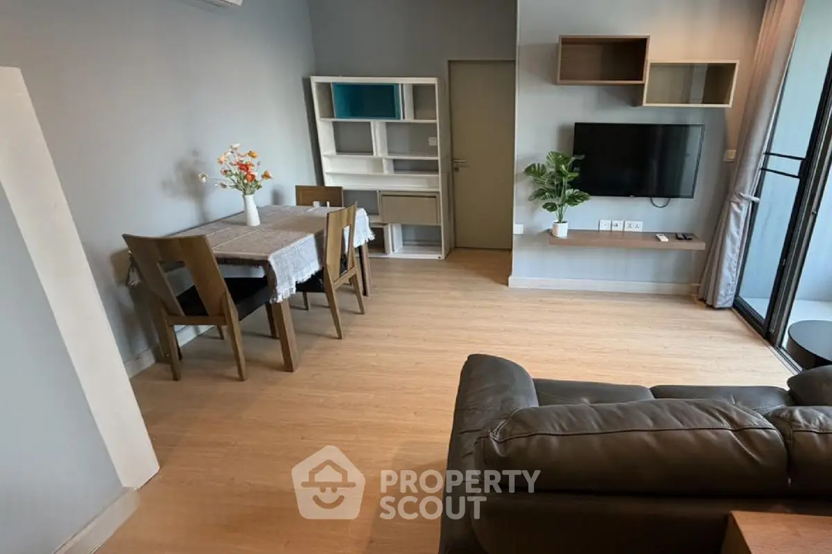 Modern living room with stylish furniture and wall-mounted TV, featuring a cozy dining area and elegant decor.