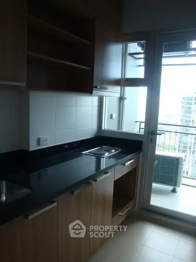 Modern kitchen with sleek cabinetry and balcony view in urban apartment