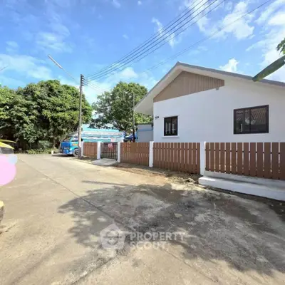 Charming single-story home with a fenced yard and lush greenery, perfect for serene living.