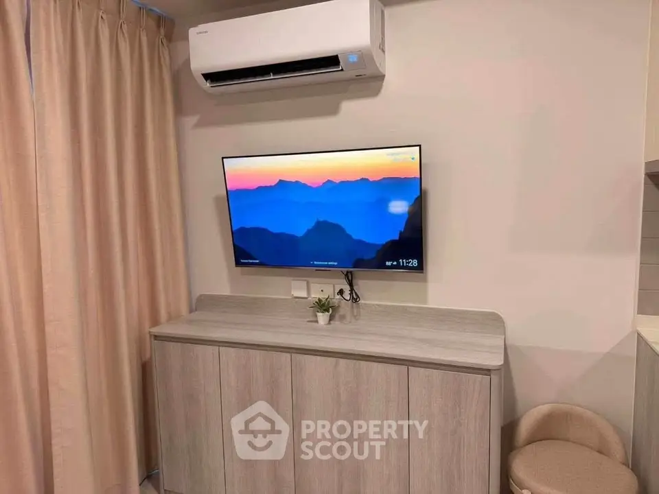 Modern living room with wall-mounted TV and air conditioning, featuring stylish wooden cabinet and cozy decor.