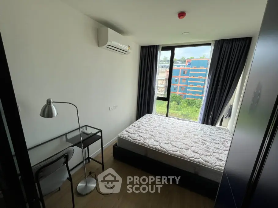 Modern bedroom with large window and study desk, featuring a comfortable bed and air conditioning.