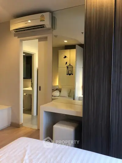 Modern bedroom with mirrored wardrobe and air conditioning in stylish apartment.