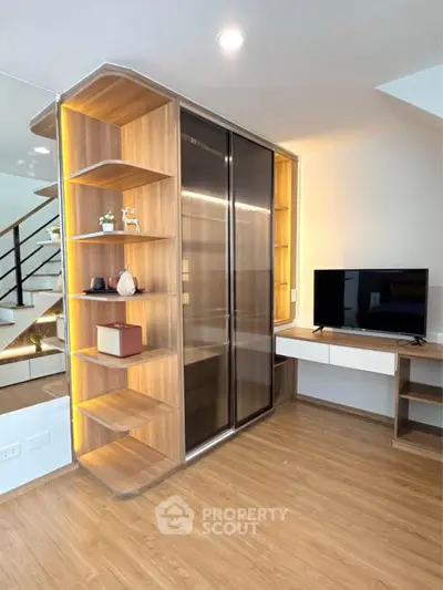 Modern living room with sleek wooden shelving and TV setup, featuring elegant lighting and contemporary design.