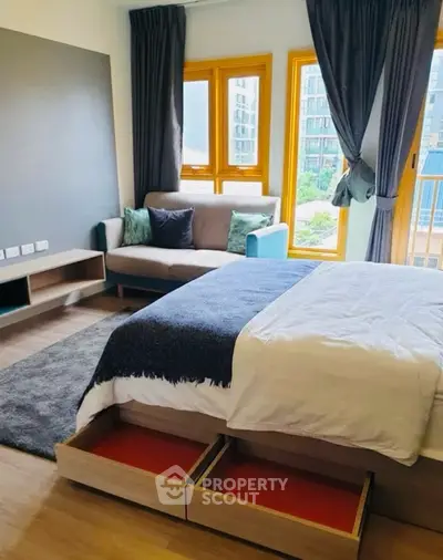 Modern bedroom with cozy sofa and large windows offering natural light