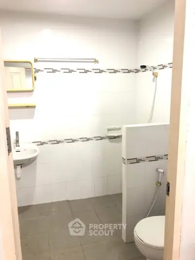 Compact bathroom with white tiles and shower area in modern apartment