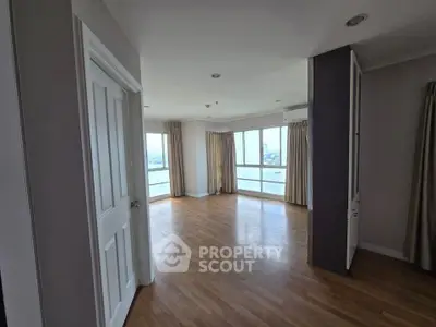 Spacious empty living room with large windows and wooden flooring in modern apartment.