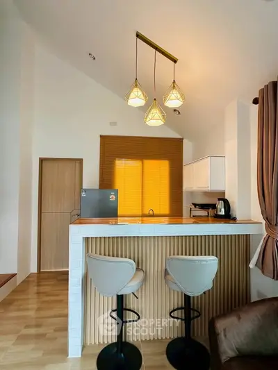 Modern kitchen with stylish pendant lights and breakfast bar seating in cozy home interior.